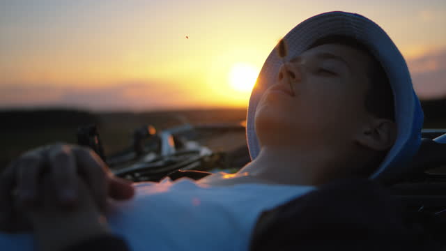 Teenager Enjoying Sunset Outdoors: Relaxing in the Field with Bike on Hilltop, Cinematic Steadicam Shot