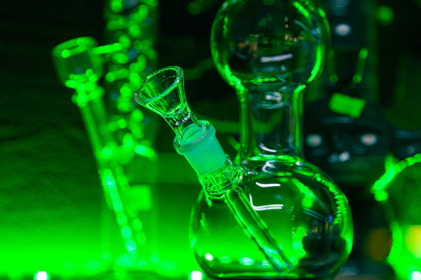 istock Glass flasks for smoking marijuana herb under green lighting. Herb smoking device. 1473777029