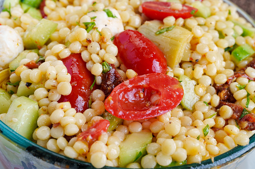 Israeli Couscous Salad Closeup Detail - Organic fresh food ingredients in colorful nutritious and light salad. Israeli Couscous, Mozzarella Cheese, Cucumbers, Tomatoes and Artichokes.
