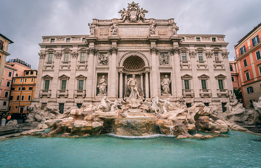 Beautiful woman in front of famous iconic Trevi Fountain at Rome, Italy.