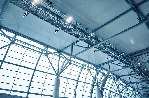 Airport terminal inside, view ceiling, window, column. Toned image in blue