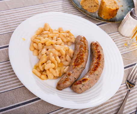 Traditional Catalan dish stewed beans with sausage on plate. Butifarra con alubias