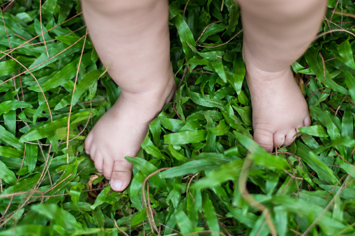 Barefoot child baby on the grass, Young mother playing with her daughter outside - Stock photo