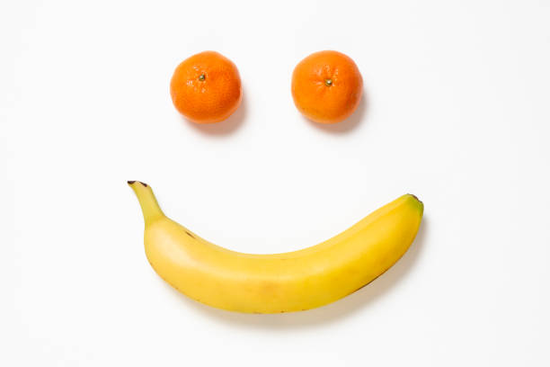 istock A smiling face made with two tangerines, and one banana, on a white background 1473792967