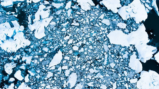 Melting Arctic ice in ocean water. Blue glacier ice covered with snow in Iceland. Global warming and climate crisis. Pure antarctic landscape aerial view.. High quality photo