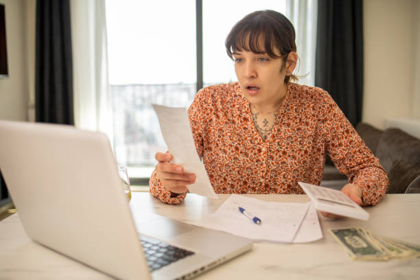 istock Young woman using calculator while going through bills and home finances 1473795070