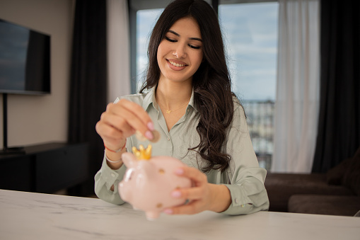 Happy young woman holding her piggy bank