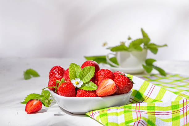 istock Fresh strawberries in a bowl on white stone table. Still life with selective focus and copy space for text 1473798434