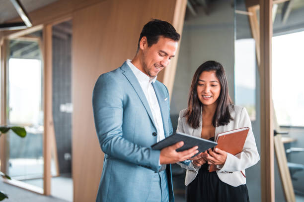 Positive Training at Work, Male Manager Shares Ideas to Female Intern Productive and positive day at work. Focused male manager sharing ideas through a tablet to female intern. business people stock pictures, royalty-free photos & images