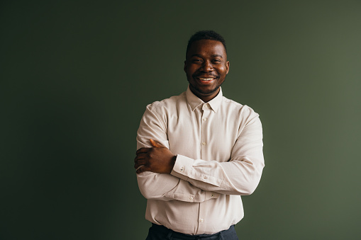 A portrait of a smiling mixed-race African-American entrepreneur standing against grey background. (studio shot, copy space)