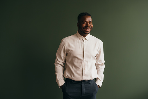 A smiling confident mixed-race African-American entrepreneur standing against grey background. (studio shot, copy space)
