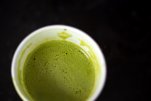 Dalgona matcha latte in a glass cup on a wooden background.