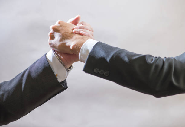 Two businessmen partner to greet each other, a firm handshake