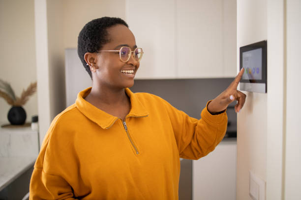 istock Young woman adjusts the temperature at home with a device on the wall 1473805795