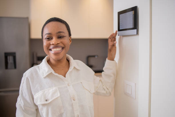 istock Young woman adjusts the temperature at home with a device on the wall 1473806401
