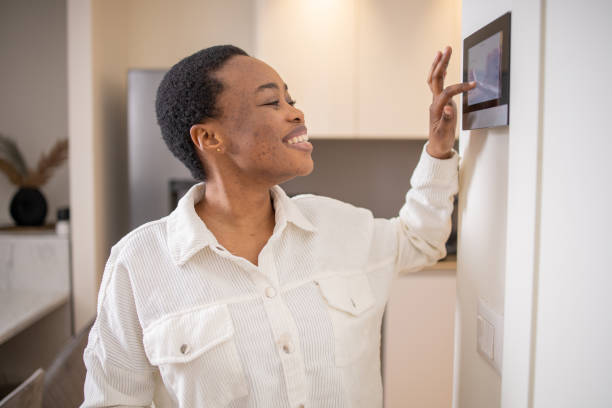 istock Young woman adjusts the temperature at home with a device on the wall 1473806402