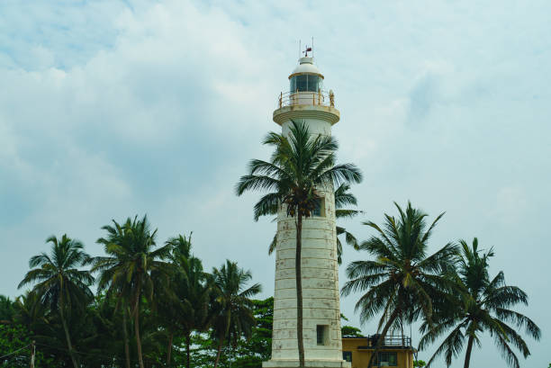 istock Old white sea lighthouse among palm trees 1473806723