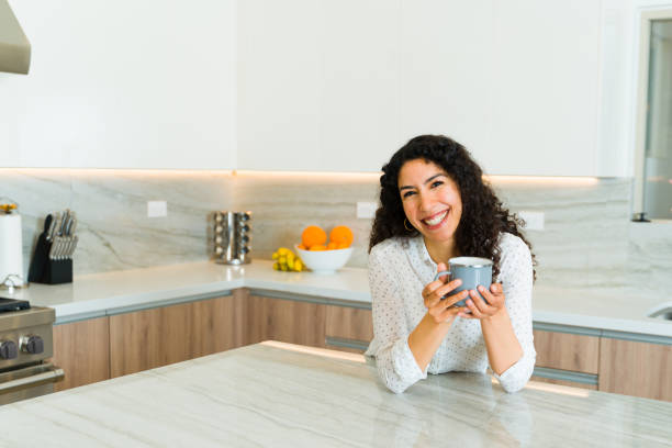 istock Happy young woman drinking coffee in a luxury kitchen 1473806951