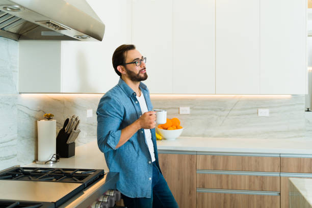 istock Caucasian man drinking coffee looking happy in his luxury kitchen 1473807032