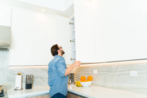 istock Rear view of a caucasian man using the white kitchen cupboard 1473807777