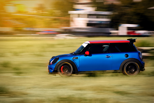 Izmir, Turkey - September 24, 2022: Fast going Blue colored Mini Cooper sports car on the road.