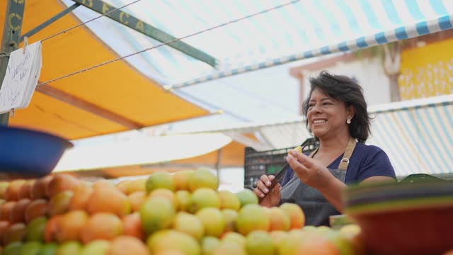 Saleswoman talking with customer while cut fruits on a street market