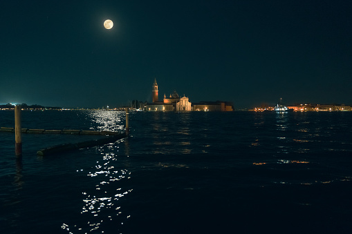 Night view of beautiful canal with medieval architecture in Venice, Italy. Santa Maria Della Salute basilica in background. Moon