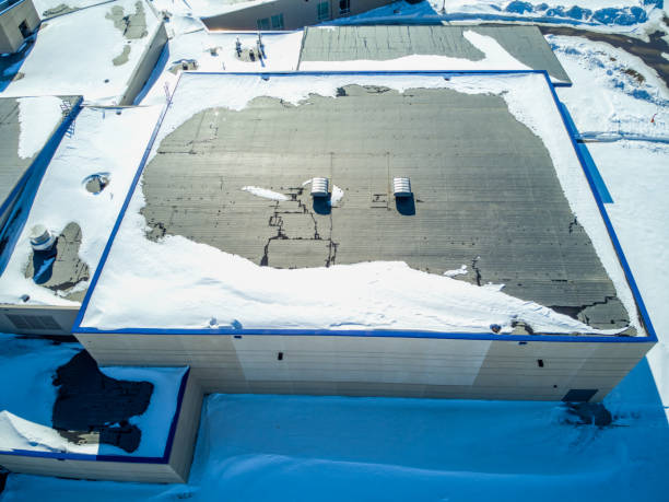 Elevated overhead drone view of a flat roofed building with snow load and ventilation units. High quality photo