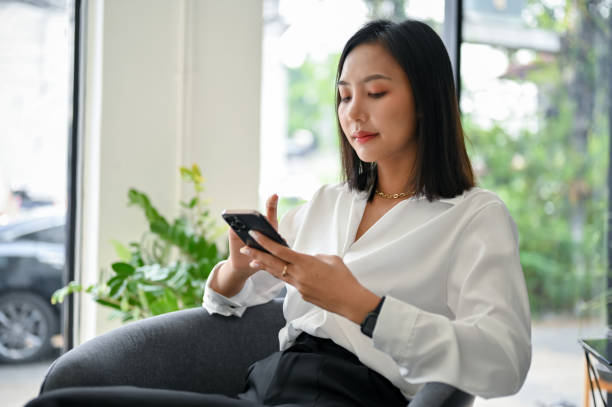 istock Gorgeous Asian businesswoman using her phone, chatting with someone or using mobile app 1473821135