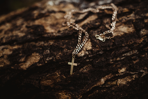 Close up of a cross necklace laying on a wood background