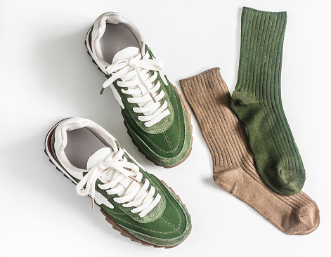 Green suede sneakers in retro style and cotton socks on a white background top view
