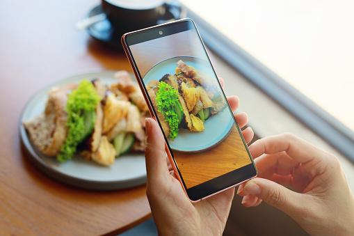 Photographing brunch at the cafe with a smartphone, personal perspective view