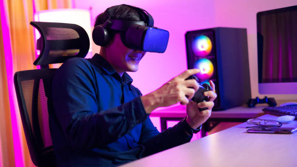 istock VR Headset. Asian man playing game on mobile phone with 3D simulation VR headset. Colorful neon light room. Esport online game. 1473830682