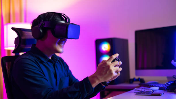 istock VR Headset. Asian man playing game on mobile phone with 3D simulation VR headset. Colorful neon light room. Esport online game. 1473830683