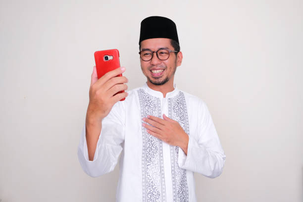 Moslem Asian man showing grateful when looking to his mobile phone Moslem Asian man showing grateful when looking to his mobile phone keluarga stock pictures, royalty-free photos & images