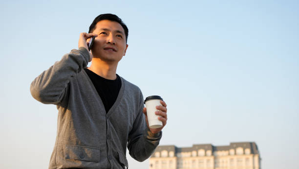 Business people use their phones while holding their coffee