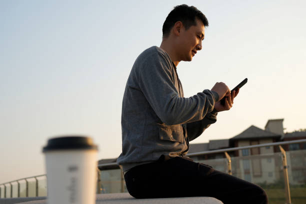 Business people use their phones while holding their coffee