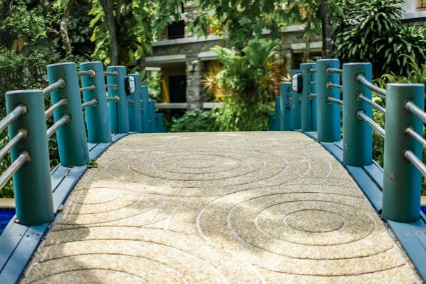 istock A stable bridge with circle wave pattern stone floor and metal railing for crossing over the pool to the other area in the garden of the resort. Shadow of plants and trees on the bridge. 1473839066