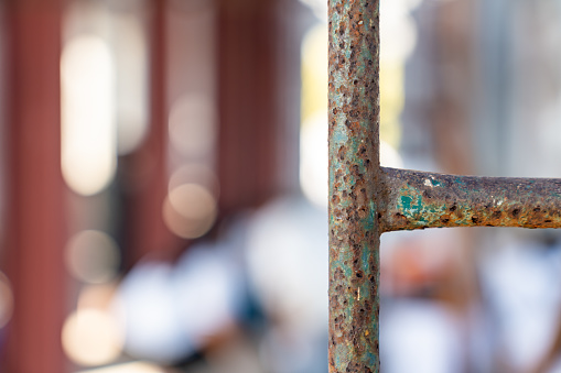 Close up shot of rusty metal pole and scaffolding on blurry construction work site background.