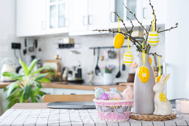 istock Easter decoration of colorful eggs in a basket and a rabbit on the kitchen table in a rustic style. Festive interior of a country house 1473843873