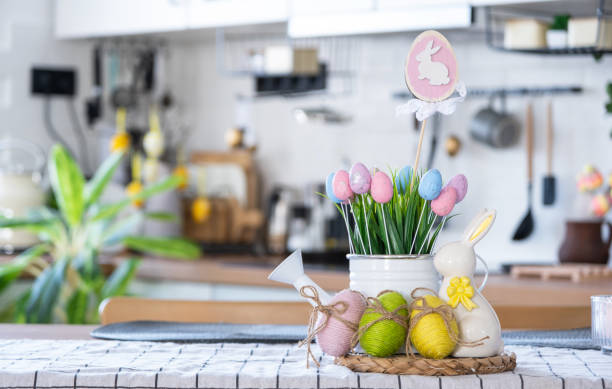 Easter decoration of colorful eggs in a basket and a rabbit on the kitchen table in a rustic style. Festive interior of a country house