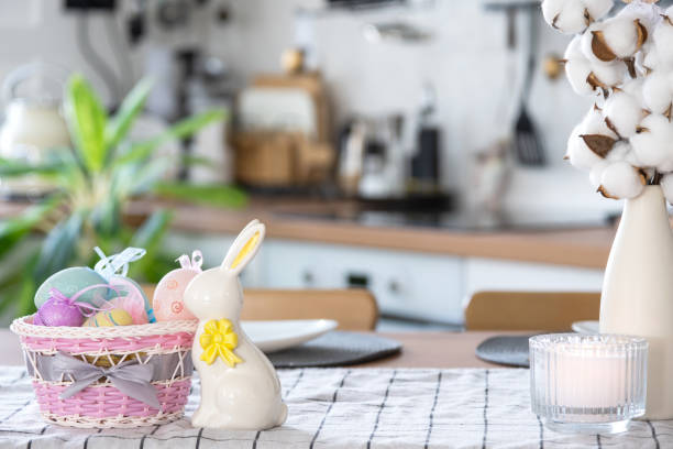 istock Easter decoration of colorful eggs in a basket and a rabbit on the kitchen table in a rustic style. Festive interior of a country house 1473843897