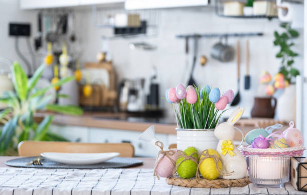 istock Easter decoration of colorful eggs in a basket and a rabbit on the kitchen table in a rustic style. Festive interior of a country house 1473843898