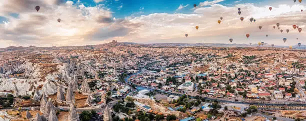 Photo of Scenic aerial panoramic view of the valley in Cappadocia with magical hot air flying balloons at sunrise. Travel and vacation in Turkiye.
