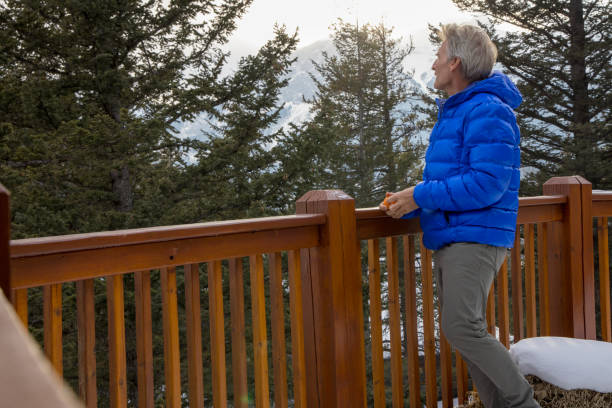 istock Mature man enjoys mandarin orange on cabin veranda 1473844330