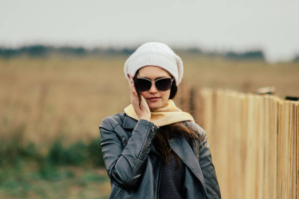 A woman wearing a bright yellow beanie along with stylish sunglasses is casually walking through the aisles of a store, browsing items