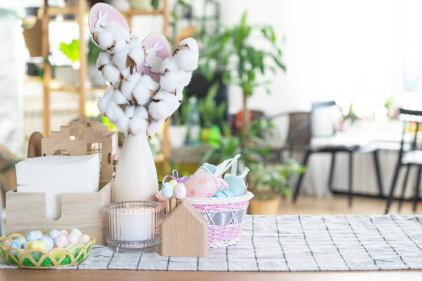 istock Easter decoration of colorful eggs in a basket and a rabbit on the kitchen table in a rustic style. Festive interior of a country house 1473847555