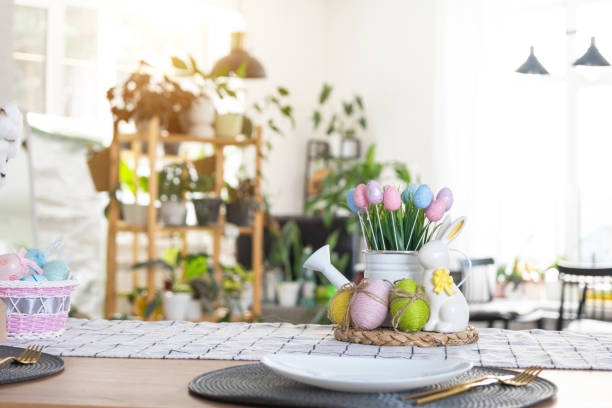 istock Easter decoration of colorful eggs in a basket and a rabbit on the kitchen table in a rustic style. Festive interior of a country house 1473847557