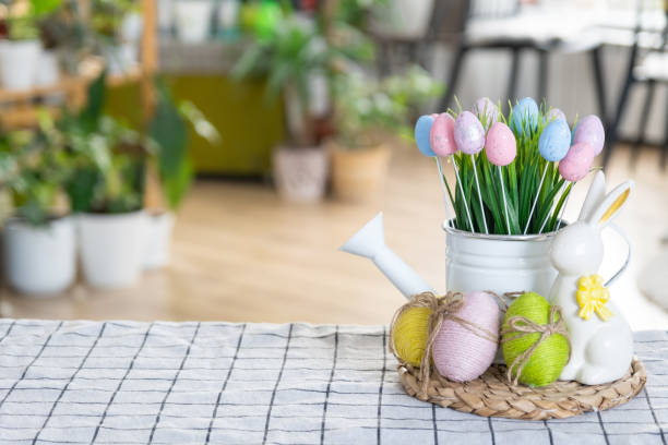 istock Easter decoration of colorful eggs in a basket and a rabbit on the kitchen table in a rustic style. Festive interior of a country house 1473847562