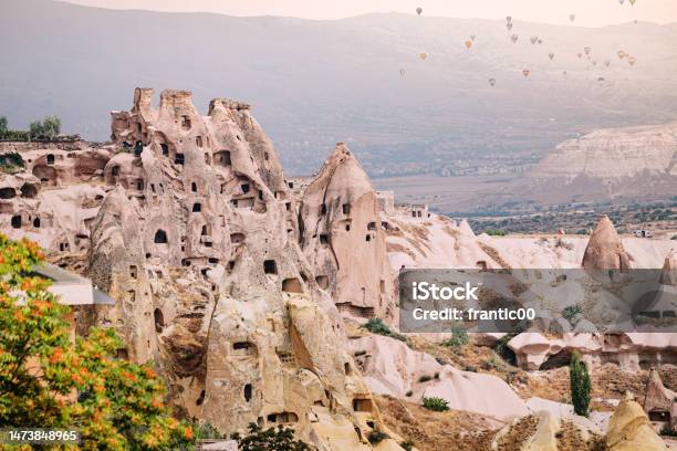 Carved Cave Town In Cappadocia Showcases Its Unique Architecture With Colorful Hot Air Balloons In The Background Capturing The Essence Of Adventure And Travel Stock Photo - Download Image Now